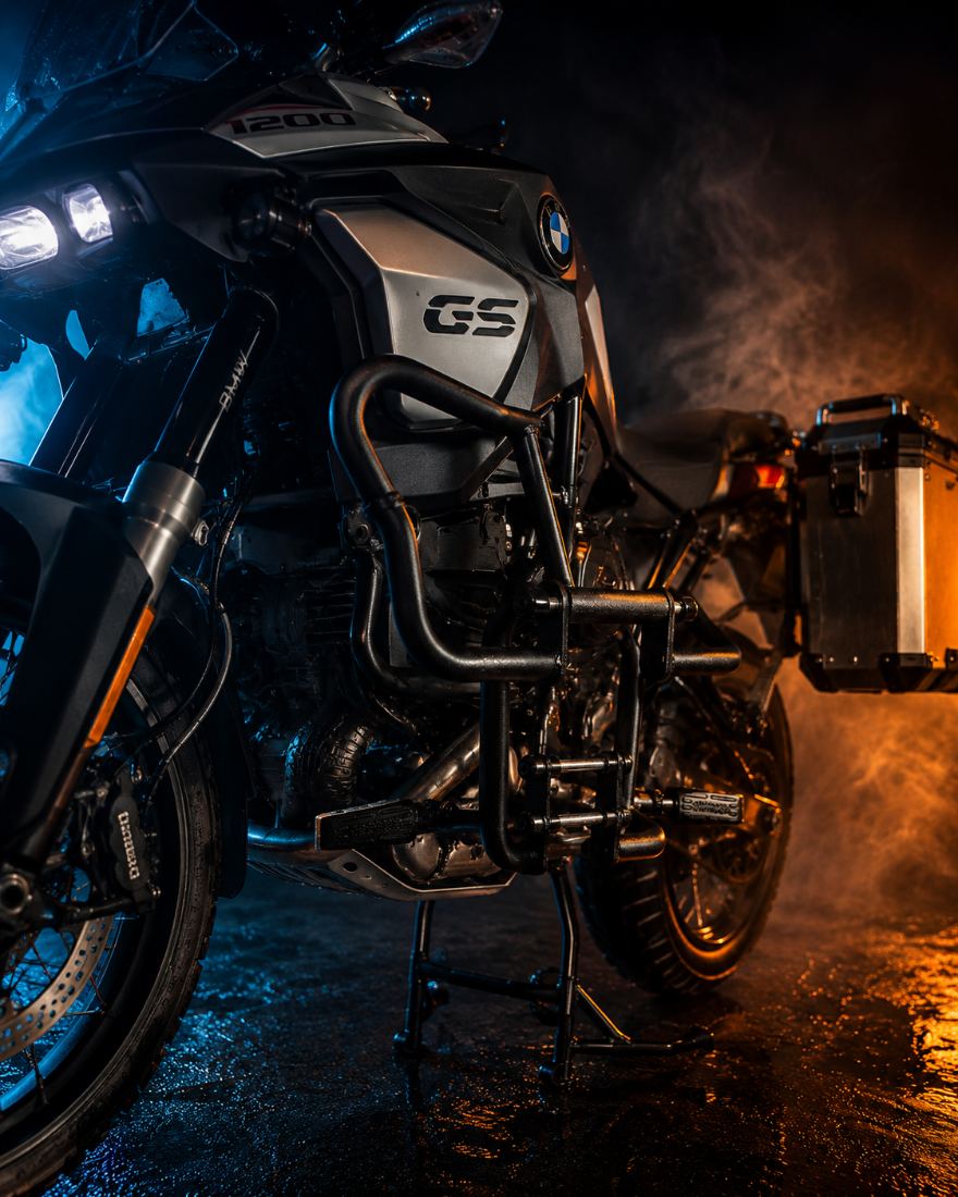 Protetor de motor preto instalado em uma BMW GS 1200, em ambiente molhado e enfumaçado